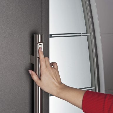 Eine Hand greift nach einem Türgriff mit Fingerscan an einer modernen Glastür.