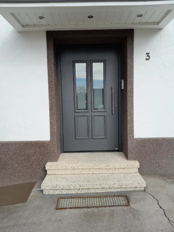 Haustür in Grau mit Steinstufen
