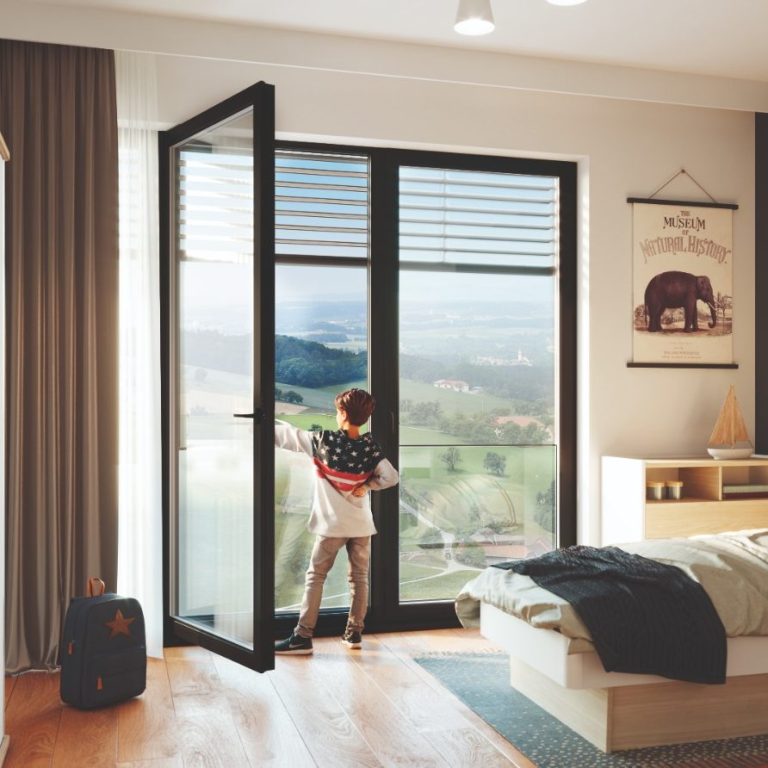 Ein Junge steht in einem Zimmer vor offenen Fenstern und schaut auf die Landschaft.