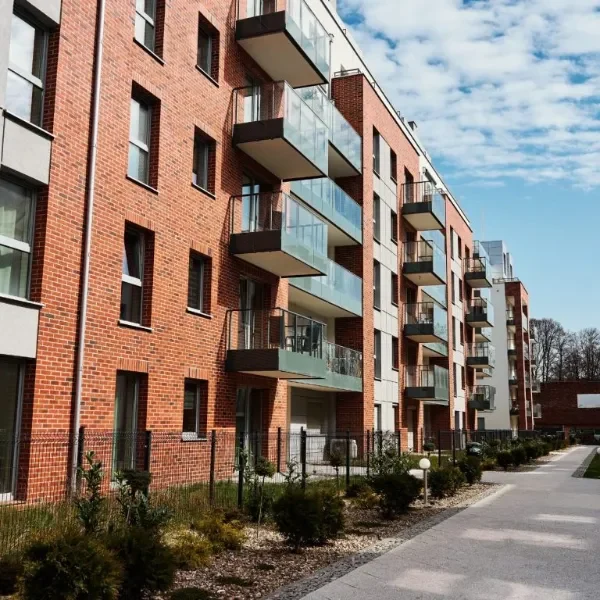 Moderne Mehrfamilienhäuser mit Balconies und gepflegtem Gehweg, hellem Himmel.