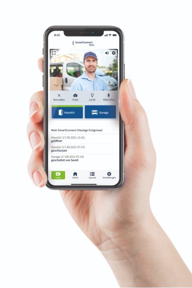 Hand hält ein Smartphone, das eine Bildaufnahme einer Türgegensprechanlage zeigt.