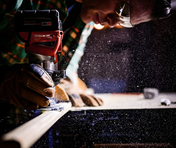 Handwerkender Mann nutzt eine elektrische Säge, Holzstaub fliegt.
