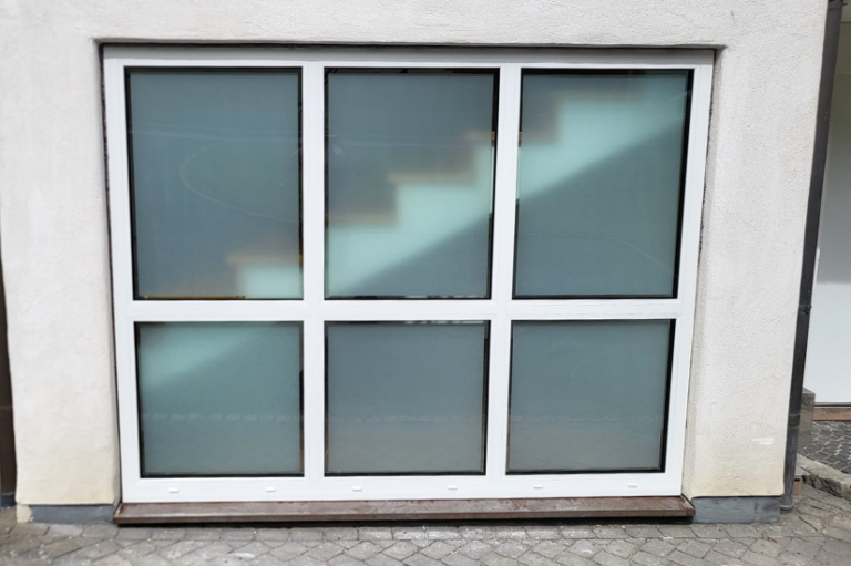 Fenster mit sechs Feldern, durch die unscharfe Treppe hinter satiniertem Glas sichtbar ist.