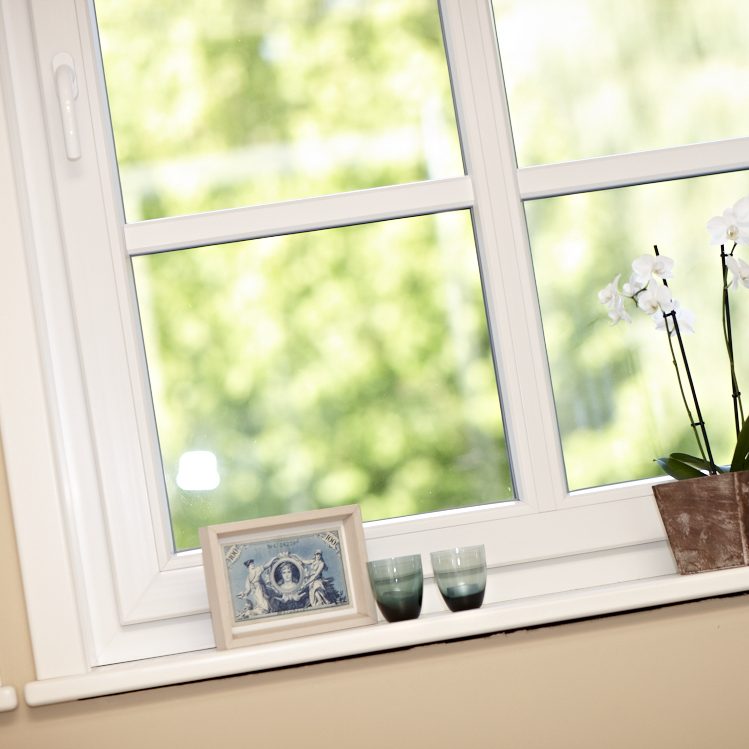 Ein Fenster mit einer Orchidee, einem Foto und zwei Gläsern auf der Fensterbank.