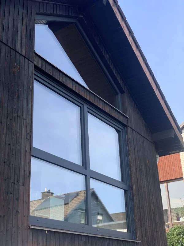 Fenster mit schwarzem Rahmen an dunklem Holzhaus