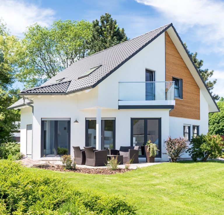 modernes zweigeschossiges Wohnhaus mit Holzverkleidung und Gartenmöbeln im Freien