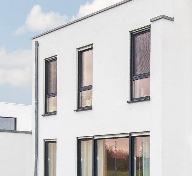 Modernes, zweigeschossiges Gebäude mit weißen Wänden und großflächigen Fenstern.